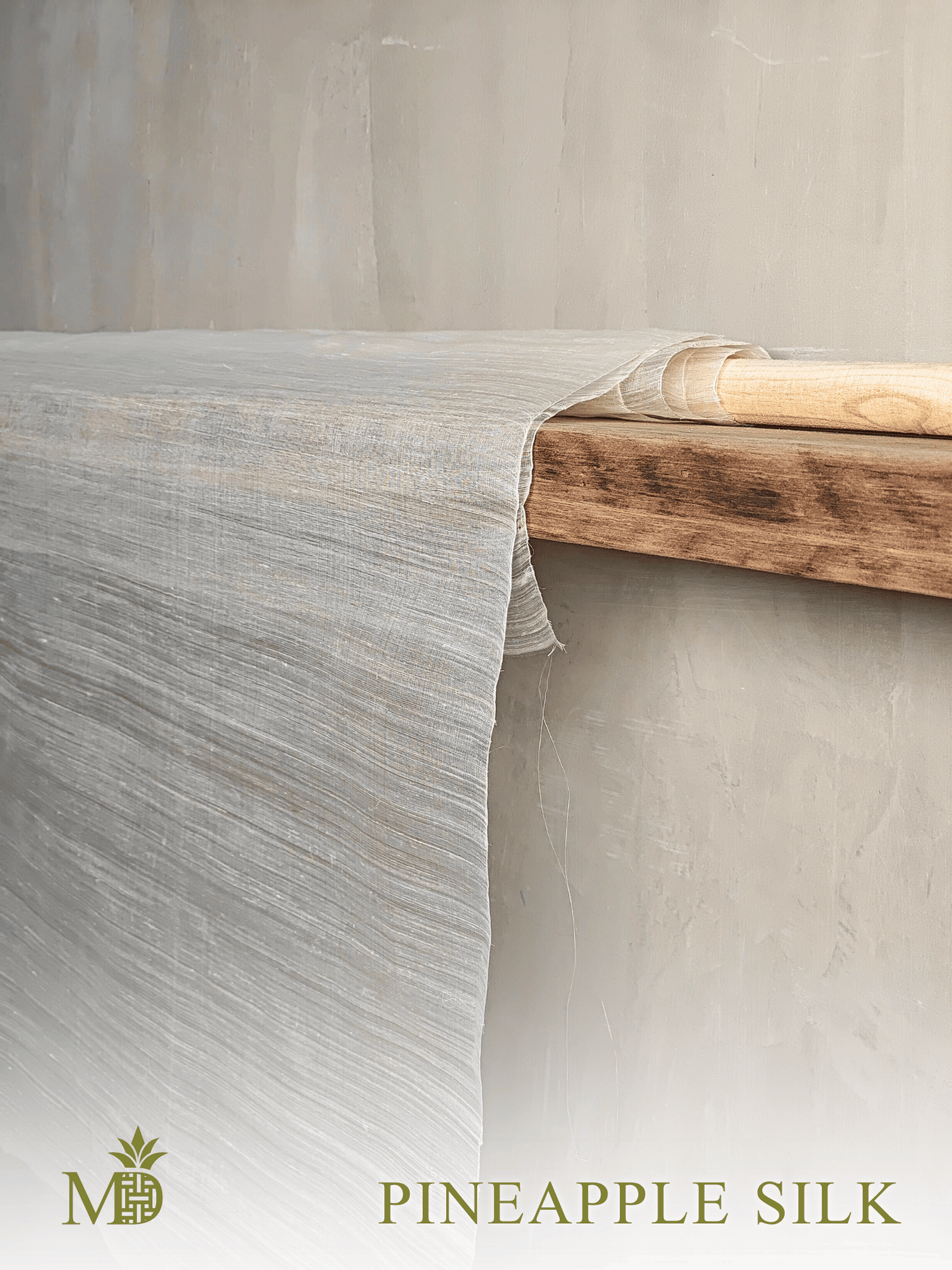 Philippine natural pineapple silk or pina silk fabric draped over a wooden shelf with a neutral background by Manila Designer, handwoven sustainable textiles from the Philippines