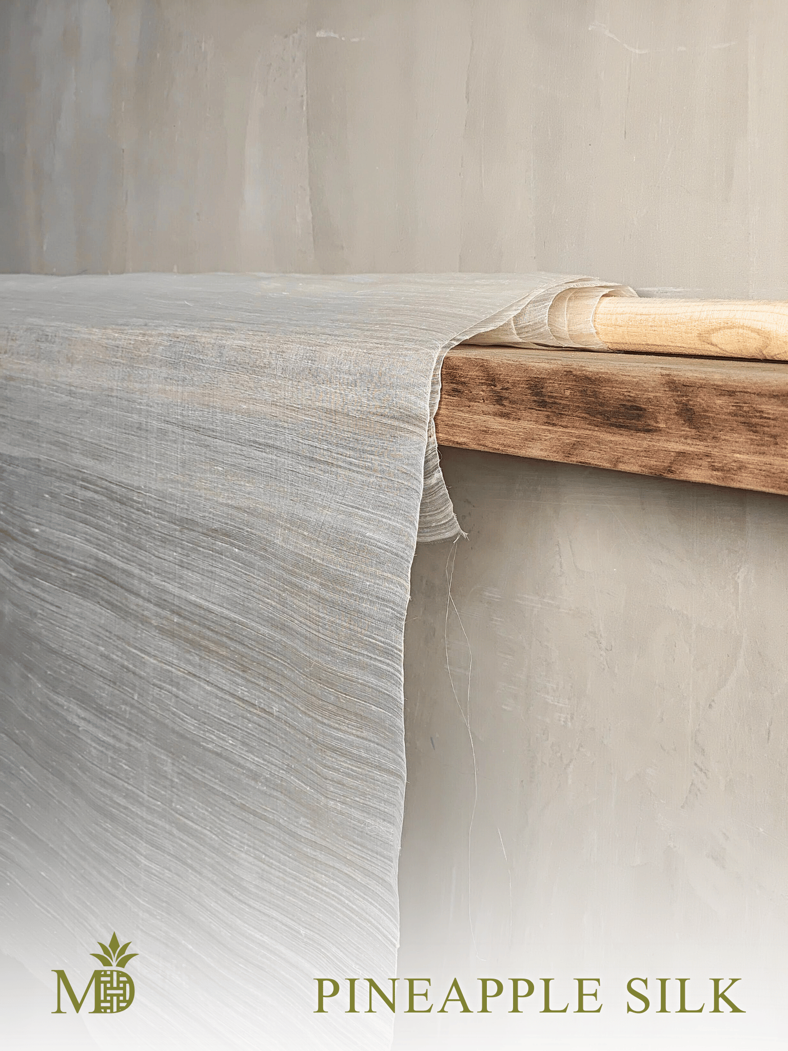 Philippine natural pineapple silk or pina silk fabric draped over a wooden shelf with a neutral background by Manila Designer, handwoven sustainable textiles from the Philippines