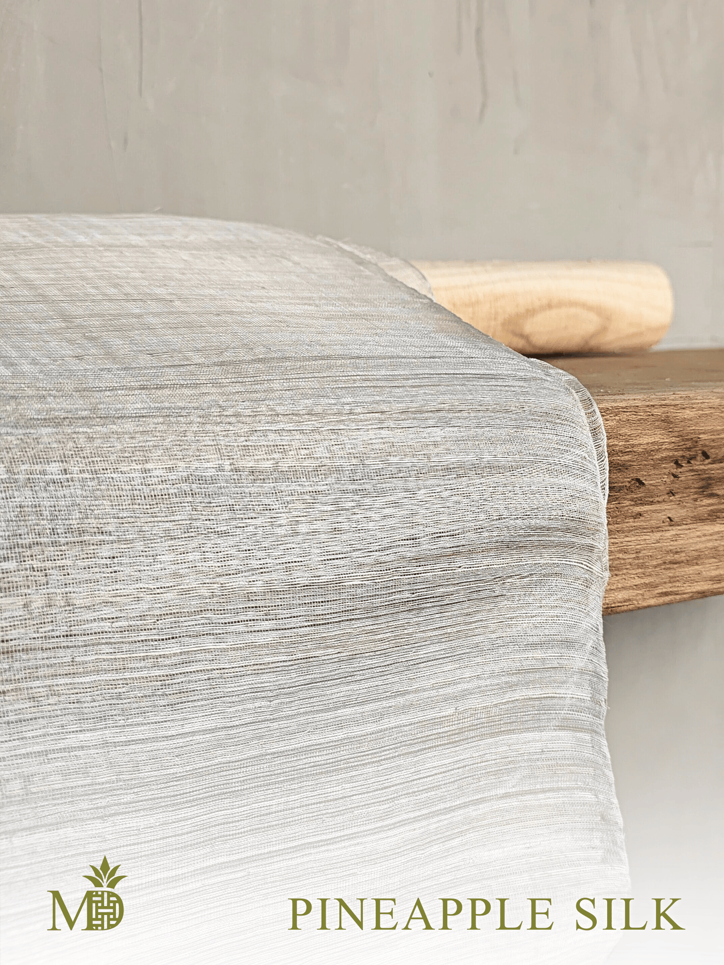 Philippine natural pineapple silk or pina Silk fabric draped over a wooden shelf with a neutral background by Manila Designer, handwoven sustainable textiles from the Philippines