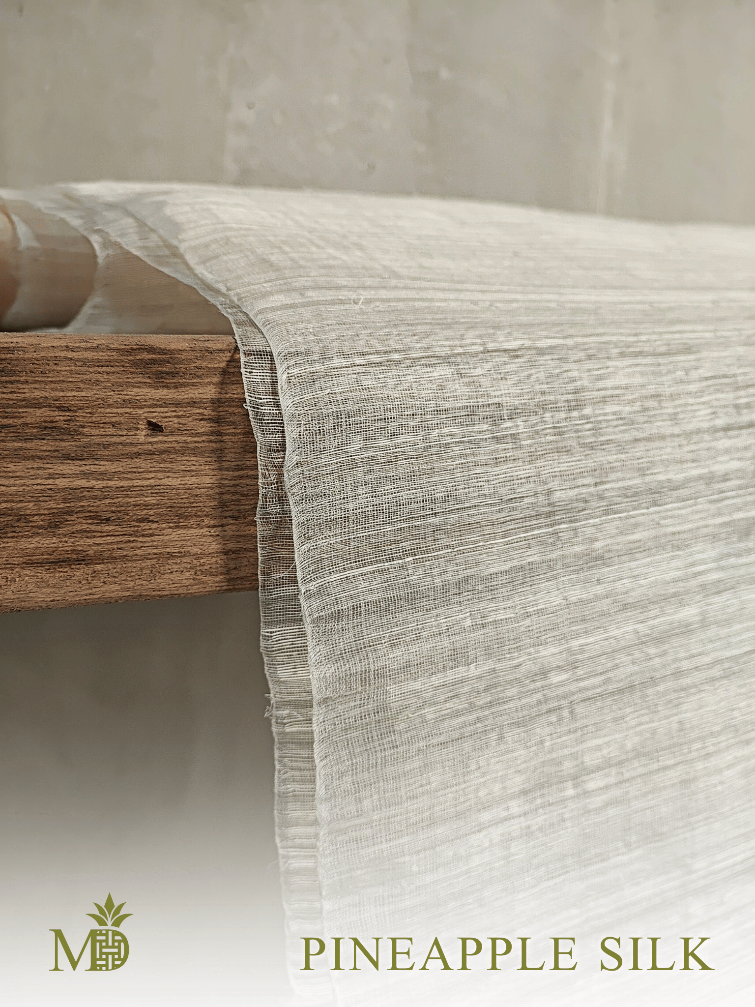 Philippine natural pineapple Silk or Pina Silk fabric draped over a wooden shelf on a neutral background by Manila Designer, handwoven sustainable textiles from the Philippines