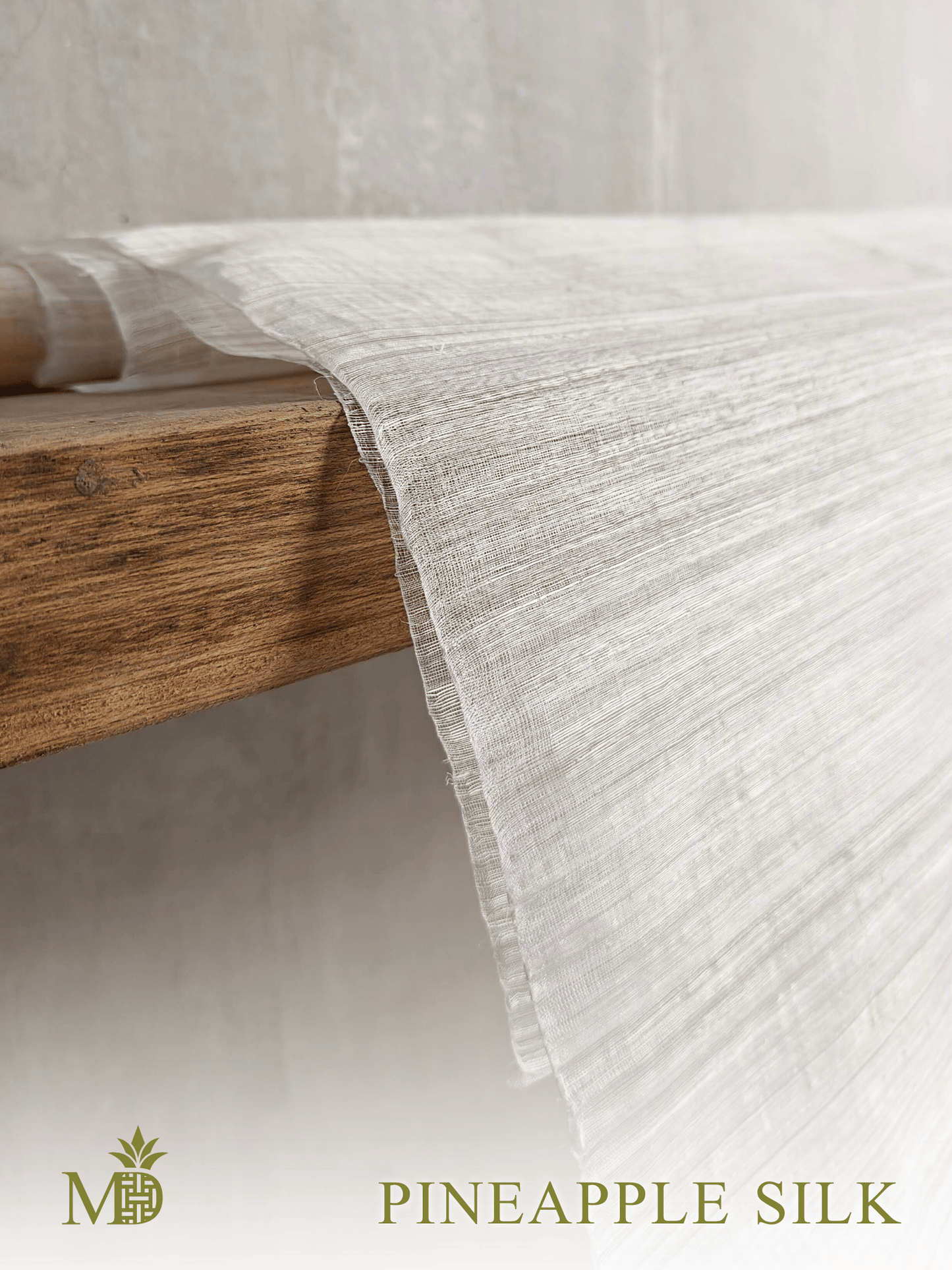 Philippine natural Pineapple silk or pina silk fabric draped over a wooden shelf on a neutral background by Manila Designer, handwoven sustainable textiles from the Philippines