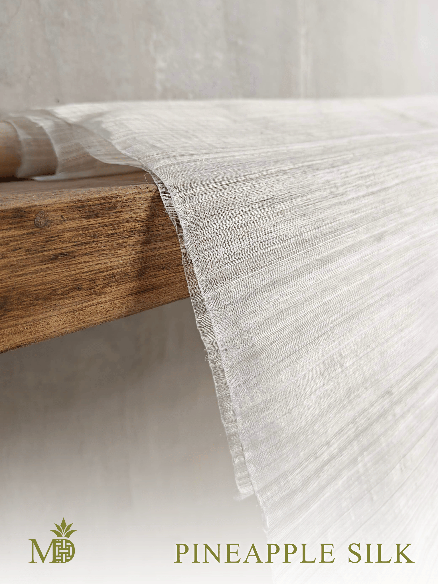 Philippine natural Pineapple silk or pina silk fabric draped over a wooden shelf on a neutral background by Manila Designer, handwoven sustainable textiles from the Philippines