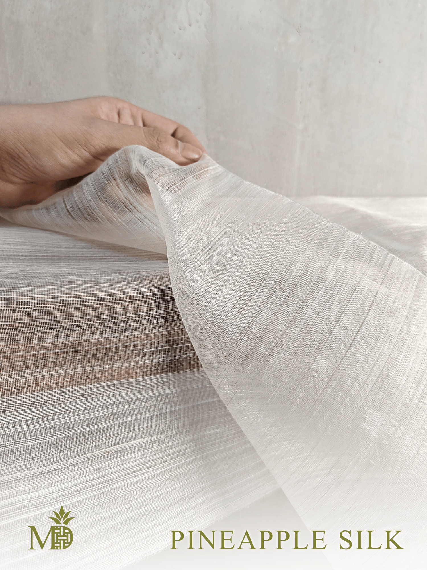 Close up of Philippine natural Pineapple silk or pina silk fabric being held with a neutral background by Manila Designer, handwoven sustainable textiles from the Philippines
