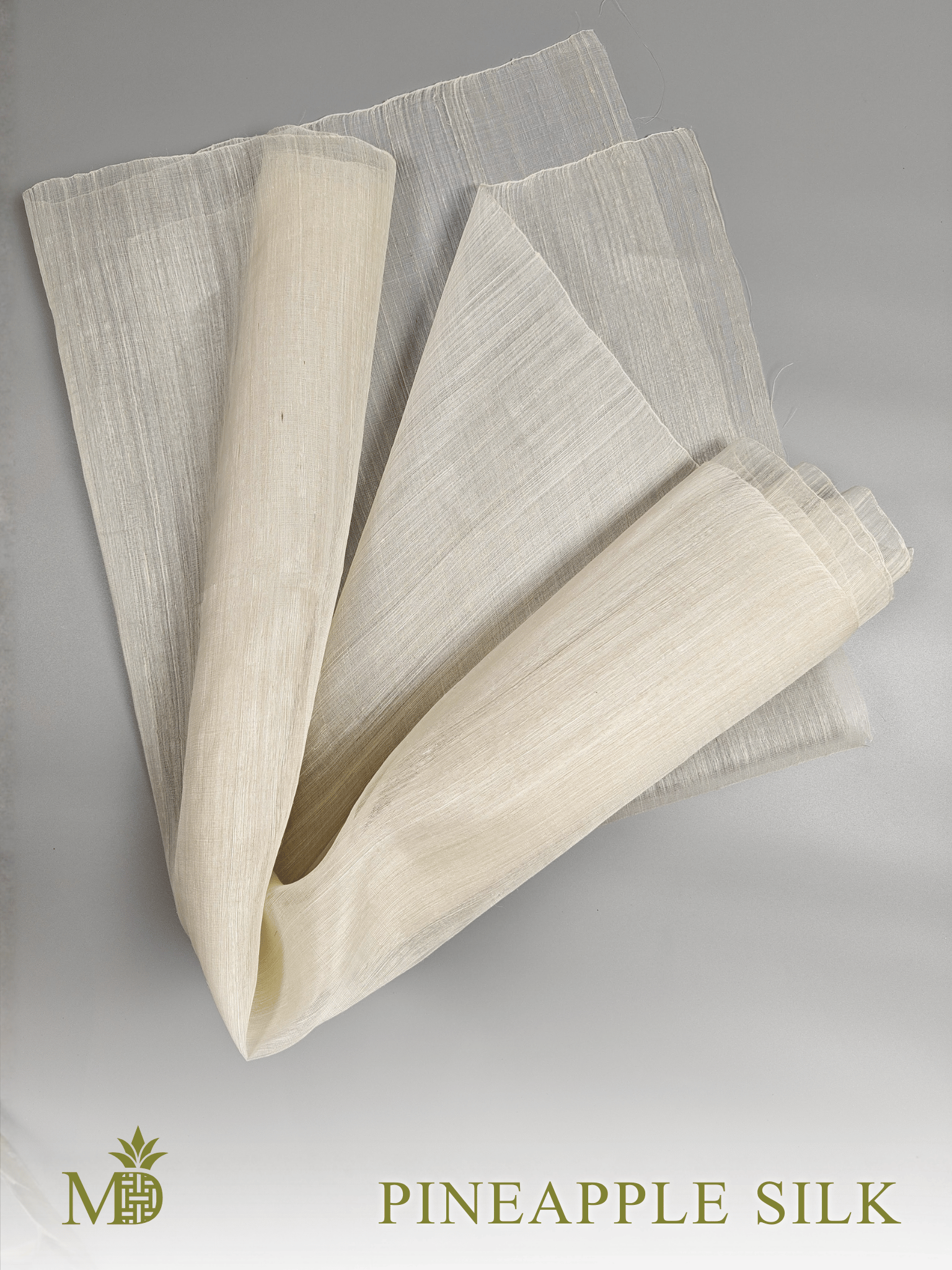 Rolled and folded Philippine natural pineapple silk or pina silk fabric on a grey background by Manila Designer, handwoven sustainable textiles from the Philippines